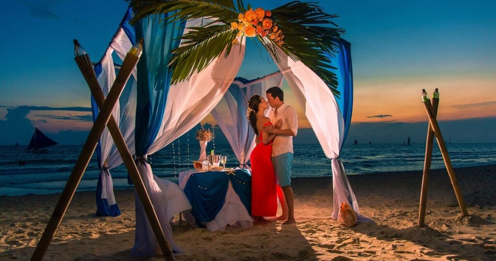 Young-couple-have-a-romantic-dinner-at-sunset-on-a-tropical-beach-usa-tour-travel-and-gears